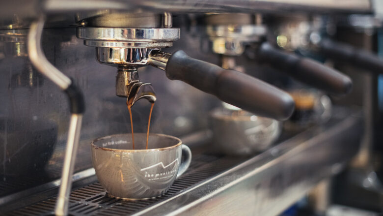 Close up of barista coffee machine pouring coffee into cup